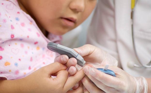 Un médico mide con un aparato la cantidad de azúcar en la sangre de un niño. 