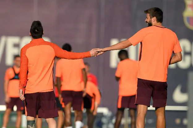 Messi y Piqué bromean durante el entrenamiento de ayer. :: afp