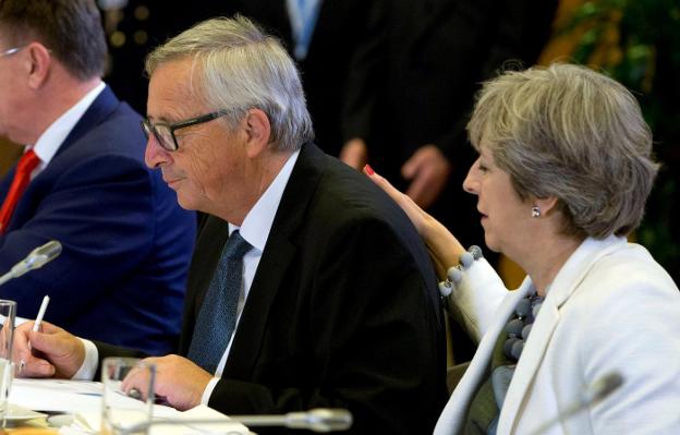 Theresa May posa su mano en la espalda del presidente de la Comisión Europea, Jean-Claude Juncker, en la segunda jornada de la cumbre europea. :: virginia mayo / efe