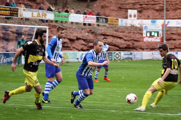 El defensa local Adrián, trata de sacar el balón jugado ante la oposición de dos de sus rivales. :: 