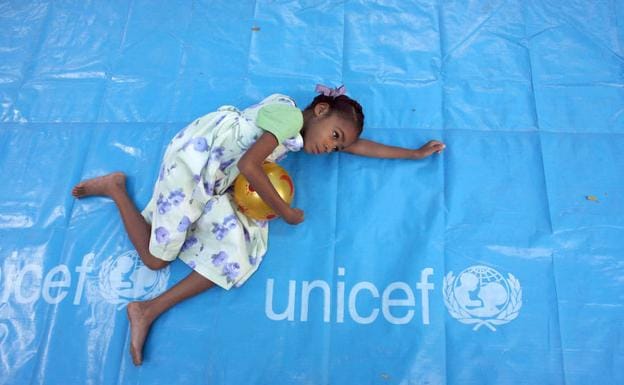 Una niña descansa en una lona de Unicef en Haití.