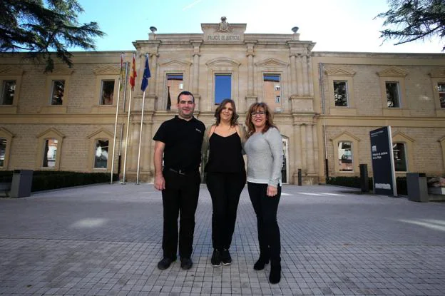 Enrique, Almudena y Sonia, sonrientes junto a la puerta principal del Palacio de Justicia. 