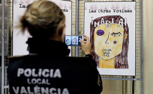 Una policía fotografía un cartel contra la violencia machista.