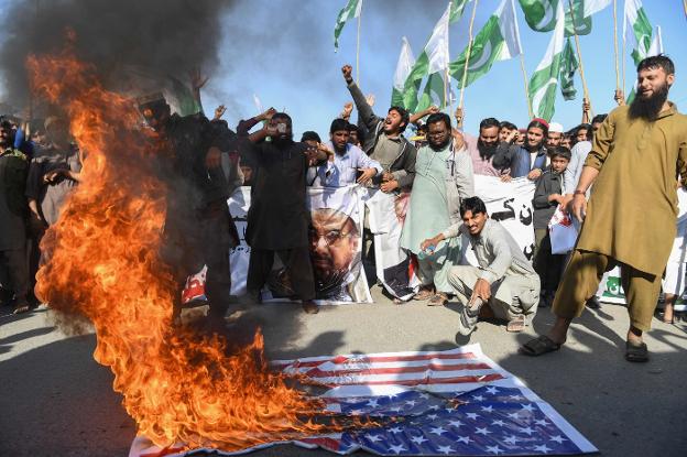Manifestantes queman una bandera americana en Karachi. :: afp
