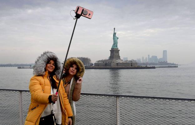 Dos turistas inglesas se fotografían con la estatua de fondo. :: afp