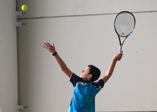 Un jugador de tenis lanza la bola al aire para efectuar el saque.
