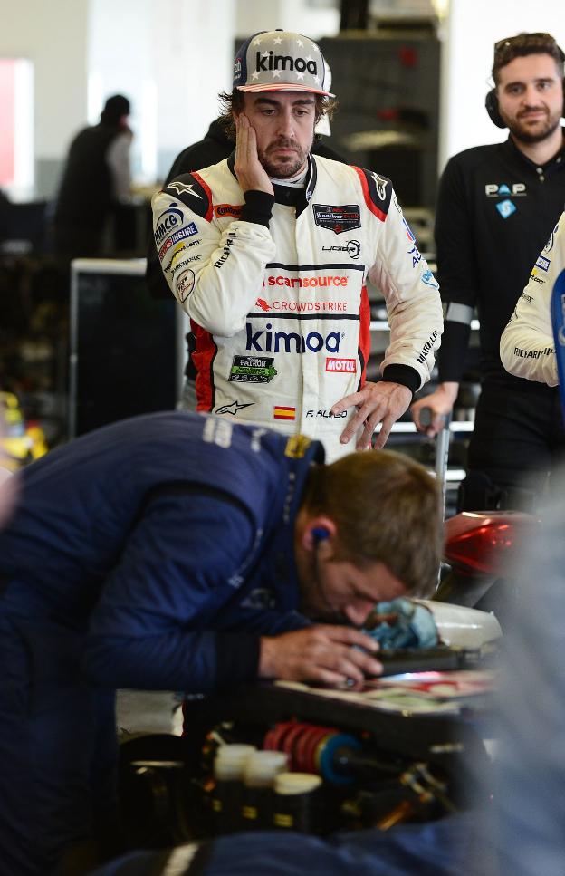 Alonso observa a uno de los mécanicos, mientras trabaja. :: efe