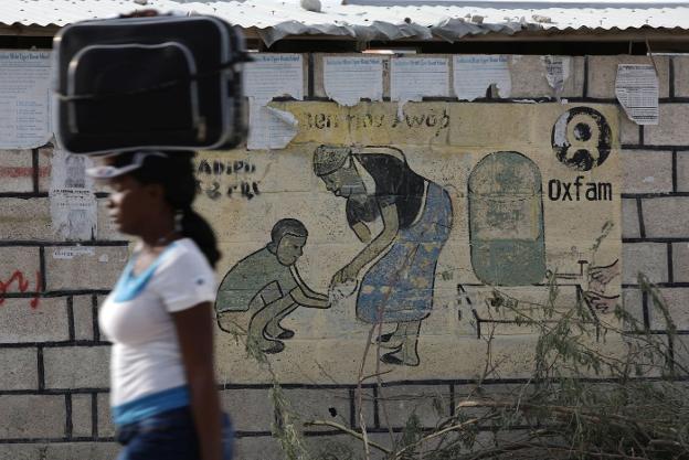 Una mujer camina en Puerto Príncipe, Haití, junto aun cartel de Oxfam. :: reuters