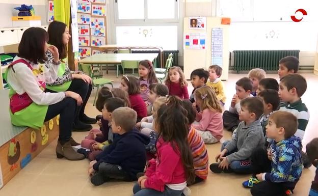 Dos alumnas en periodo de prácticas hablan a los niños de educación infantil. 