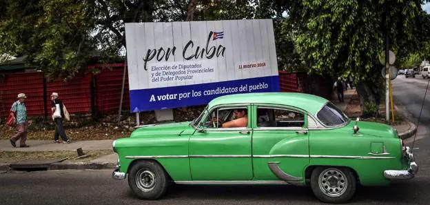Un coche clásico circula por una calle de La Habana en la que se observa un cartel alusivo a las elecciones que hoy se celebran en Cuba. :: alejandro ernesto / efe