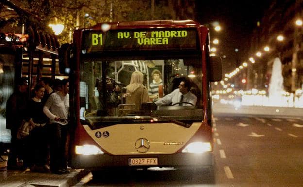 Varios usuarios suben al autobús nocturno. 