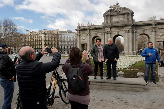 Varios turistas se fotografían ante la Puerta de Alcalá, en Madrid. :: Chema Moya / Efe