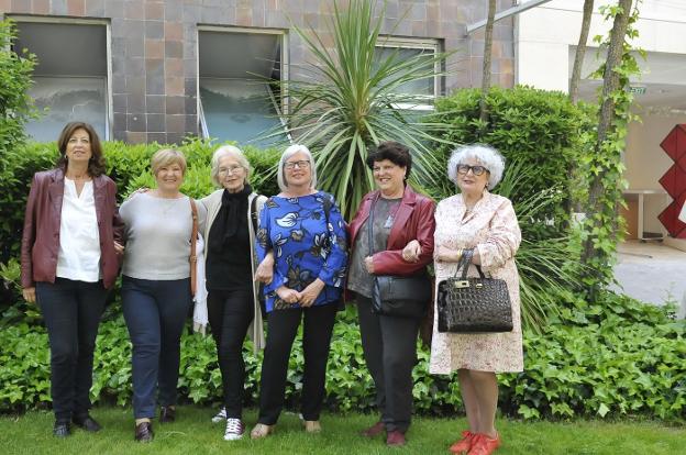 Eugenia Parejo, tercera por la izquierda, con otras cinco protagonistas del documental. Abajo, las 14 mujeres retratadas en un mural en Berga. 