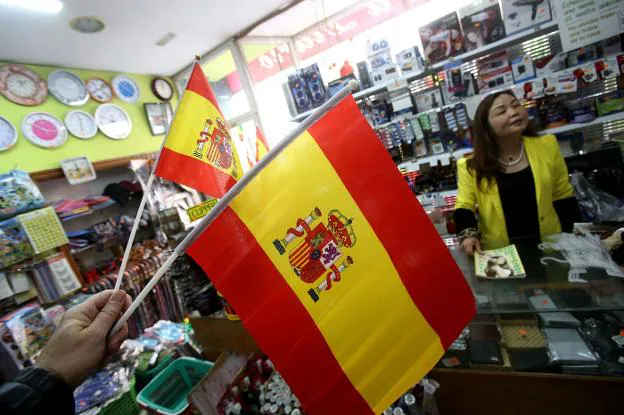 Un cliente compra banderas en un 'chino'. :: juan marín