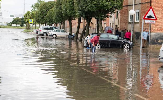 Vecinos de Santo Domingo se afantan en achicar agua tras la tormenta.