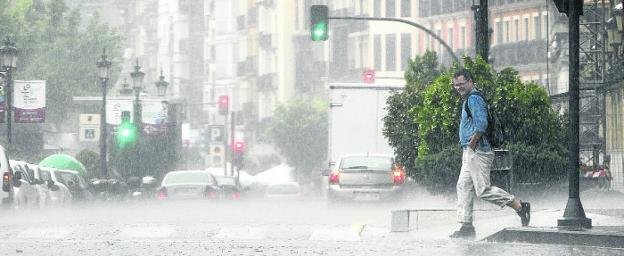 Un peatón cruza de Muro de la Mata hacia el Espolón en pleno diluvio, ayer tarde. :: Justo Rodríguez
