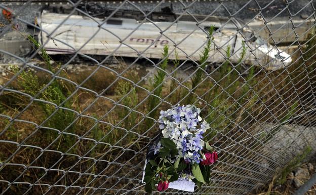 Flores colgadas en la valla que bordea las vías donde se encuentran los restos del tren. 