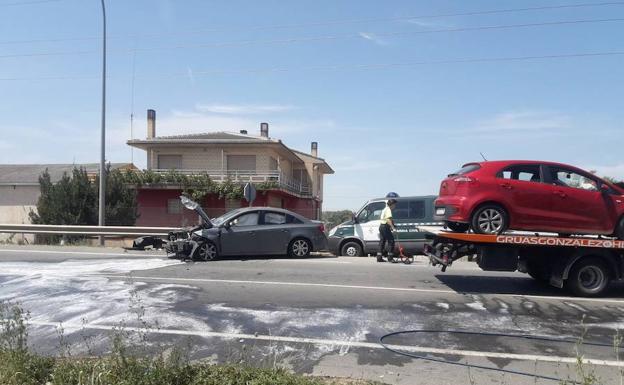 La Guardia Civil toma medidas sobre el terreno mientras una grúa se lleva uno de los vehículos implicados en el accidente. 