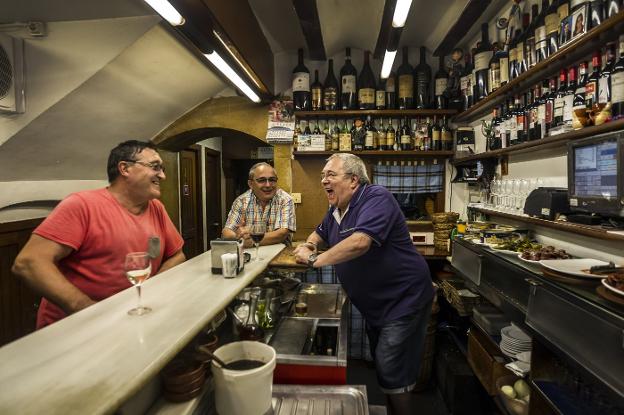 Manolo, ayer al mediodía, fotografiado al frente de su barra de la calle San Agustín, de tertulia entre risas con dos clientes. :: justo rodríguez