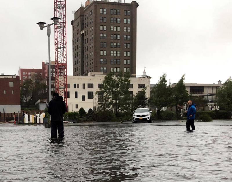 Algunas personas cruzan las calles anegadas de agua por el temporal a su paso por Wilmington.