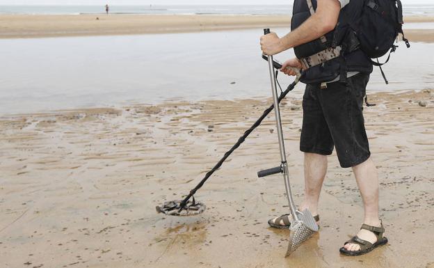Un hombre rastrea la playa en busca de metales. 