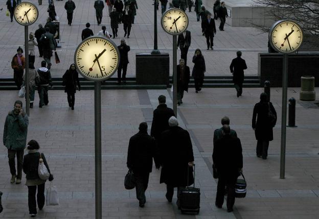 Varios peatones caminan entre relojes en el barrio londinense de Canary Wharf. :: A. WINNING / reuters