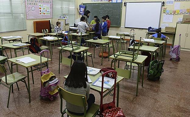 Una profesora atiende a un grupo de alumnos en un aula. 