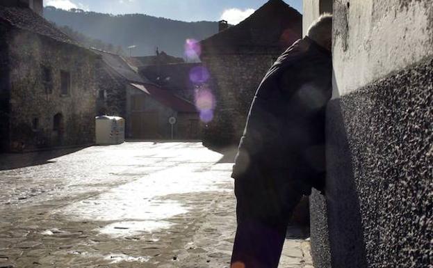 Un hombre conversa con un vecino a través de la ventana.