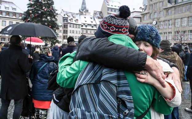 Varias personas se abrazan tras un homenaje a las víctimas de Estrasburgo. 