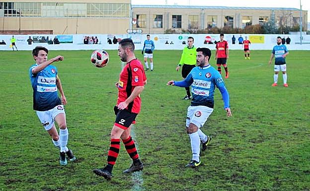 Jorge García, en el centro, trata de controlar un balón entre dos rivales. 