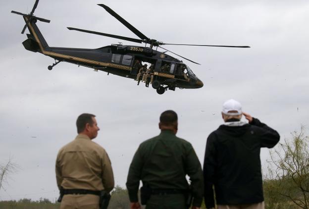 Trump, junto a miembros de la patrulla fronteriza de Texas, saluda al helicóptero que vigila Río Grande. :: Leah Millis / reuters