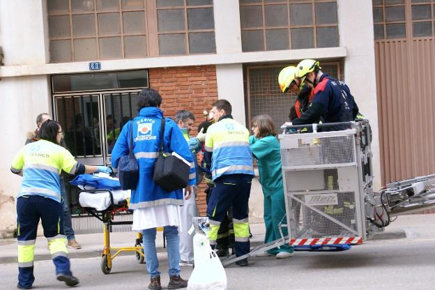 Un médico sujeta la cabeza del niño, mientras le trasladan de la cesta de los bomberos a la camilla. 