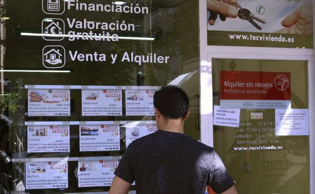 Una persona observa las ofertas del escaparate de una inmobiliaria. 