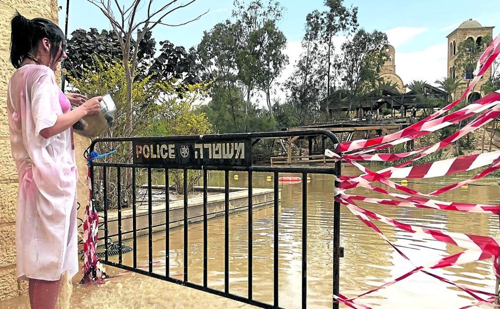 Una peregrina se purifica en la orilla del Jordán, cuyo acceso en Qasr el Yahud ha sido vallado por la Policía para impedir el paso hacia aguas más profundas. 