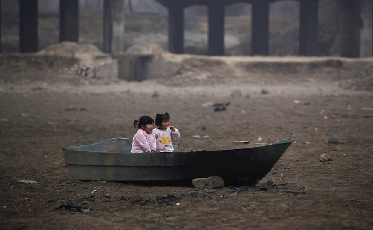 Dos niñas juegan en una barca abandonada en un lago seco en Zhengzhou, en la provincia china de Henan.