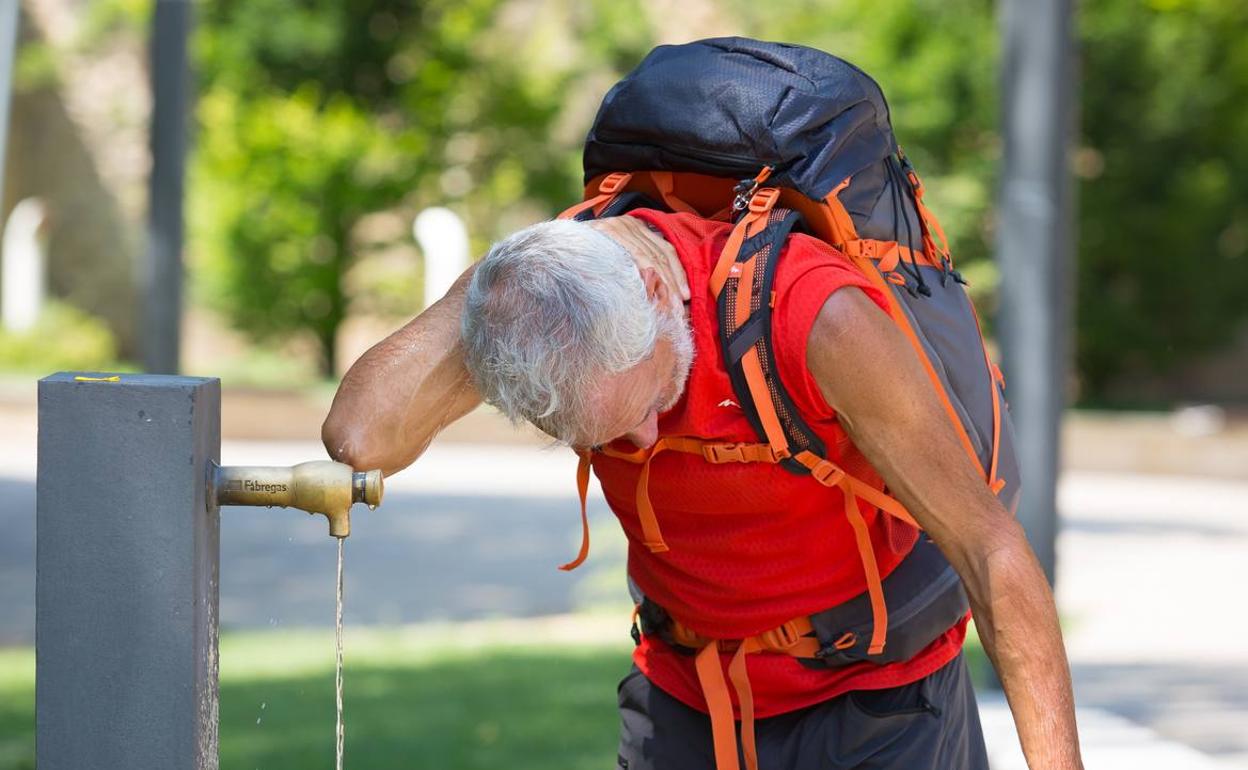 Un hombre se refresca en una fuente.