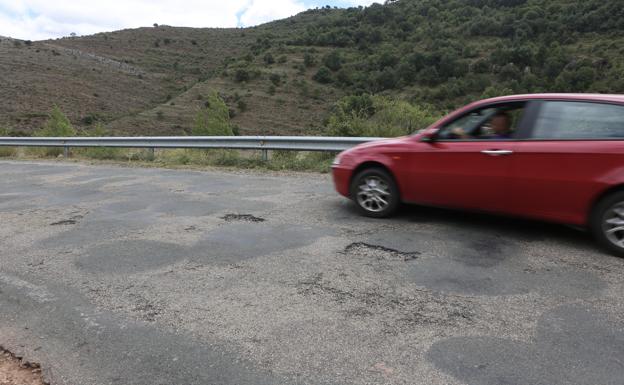 Un vehículo esquiva dos baches entre Villavelayo y Mansilla. 