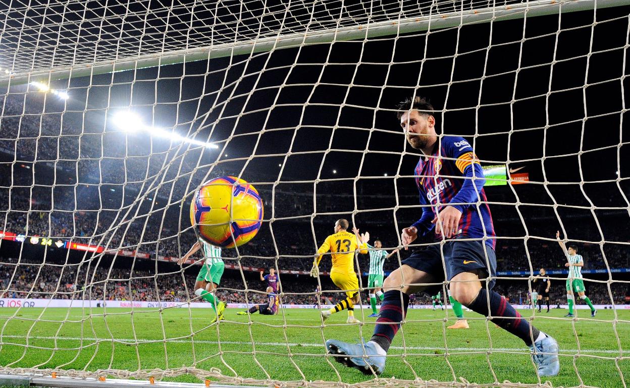 Leo Messi recoge el balón del fondo de la red ante el Betis.
