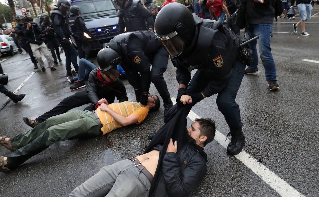 Agentes de la Policía nacional arrastrando a ciudadanos que trataban de evitar su entrada a un centro electoral en Barcelona, durante el referéndum catalán del 1-O. 