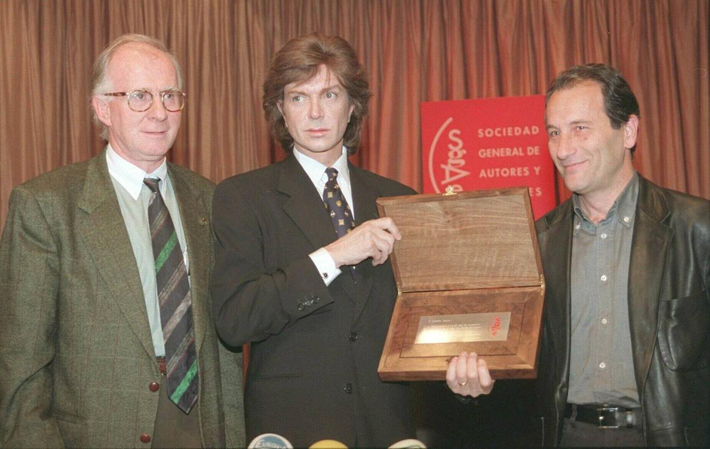 Camilo Sesto muestra la placa conmemorativa que le entregó el presidente de la SGAE Eduardo Bautista (i) y el director general de BMG Ariola, José María Cámara, en reconocimiento a su carrera, en 1997.