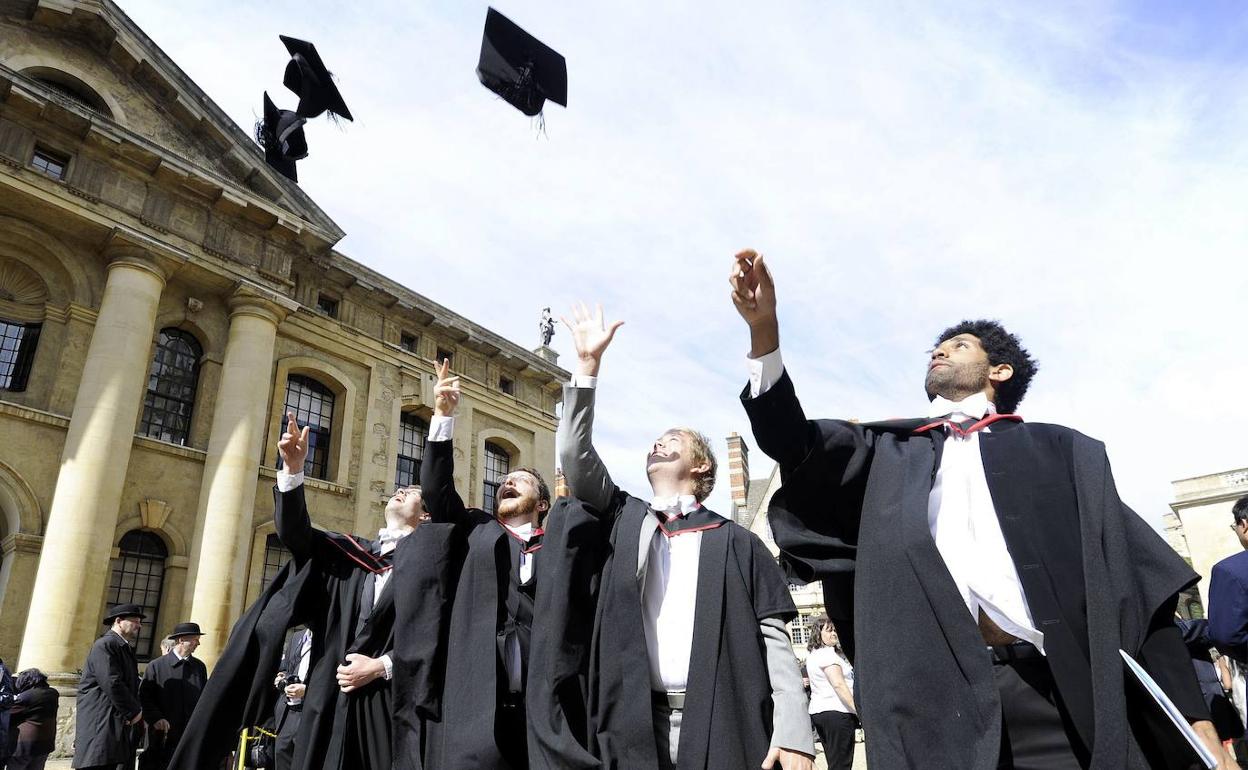 Un grupo de estudiantes lanza sus birretes al aire tras la ceremonia de graduación en la Universidad de Oxford (Inglaterra).