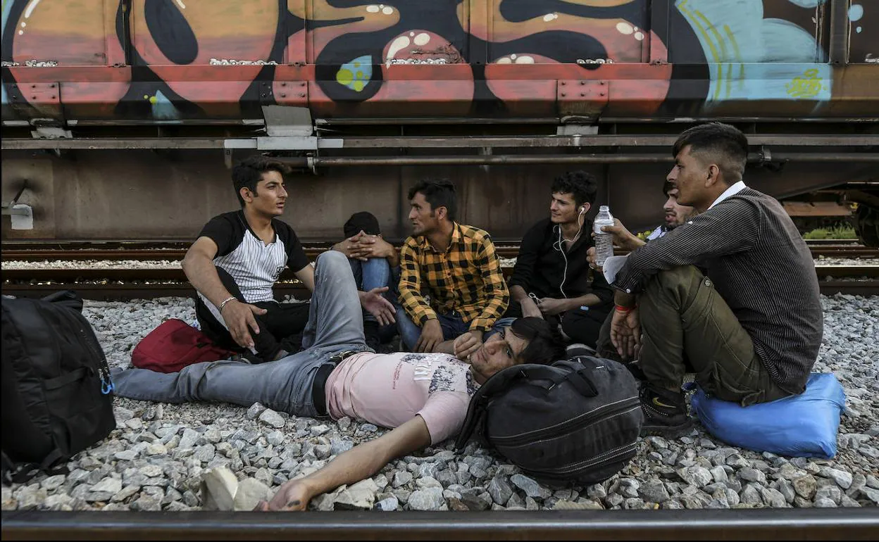 Un grupo de migrantes espera en la vía férrea que une Grecia con Macedonia.