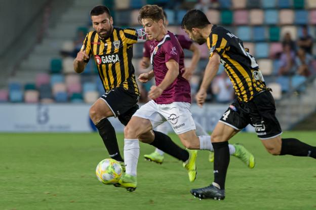 Joseba conduce el balón ante dos jugadores del Barakaldo