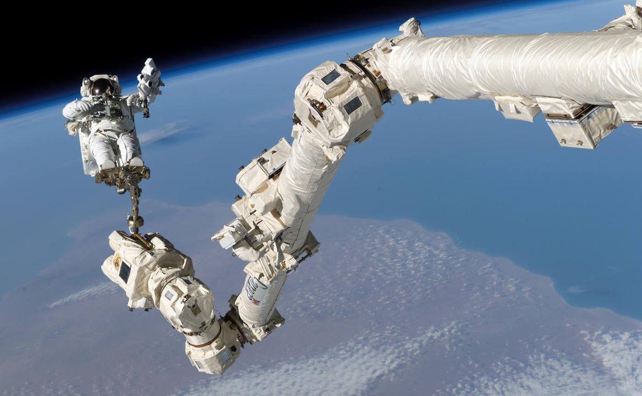 Un astronauta unido a uno de los brazos de la Estación Espacial Internacional.