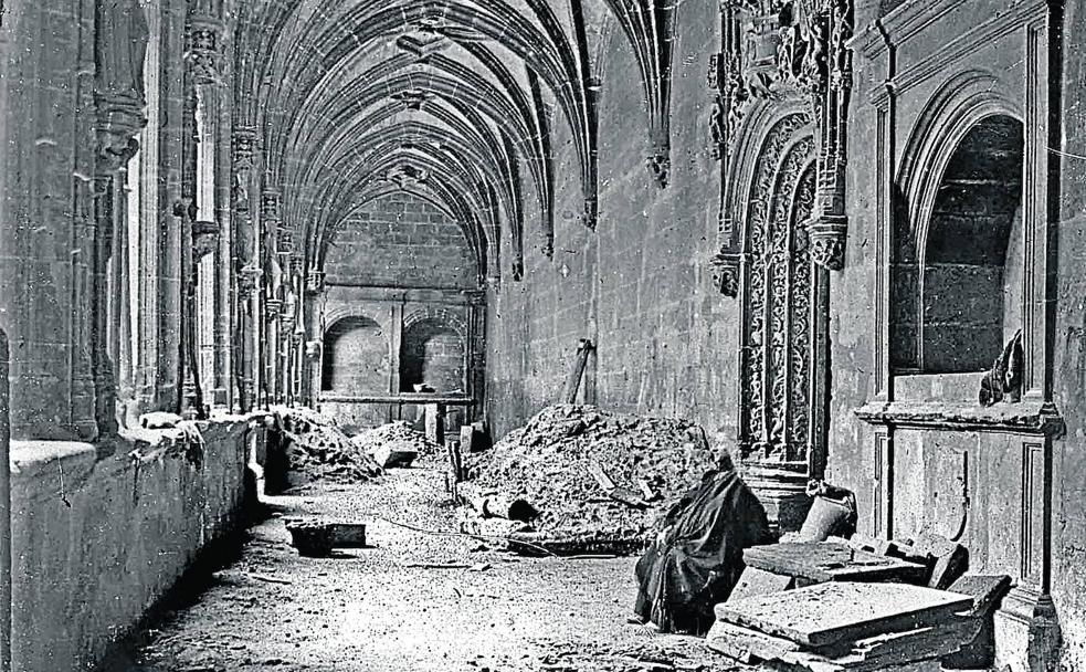 Un monje, con la cabeza casi borrada, en el claustro bajo del monasterio, con el suelo levantado para su pavimentación.