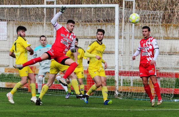 Un futbolista del Varea intenta rematar ante la mirada de Escribano y de la zaga del Yagüe. 