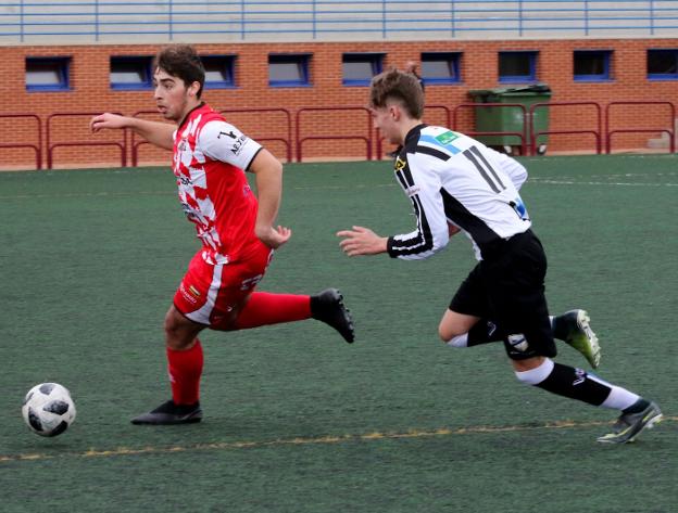 Un futbolista del Varea conduce el cuero ante la presión de un rival