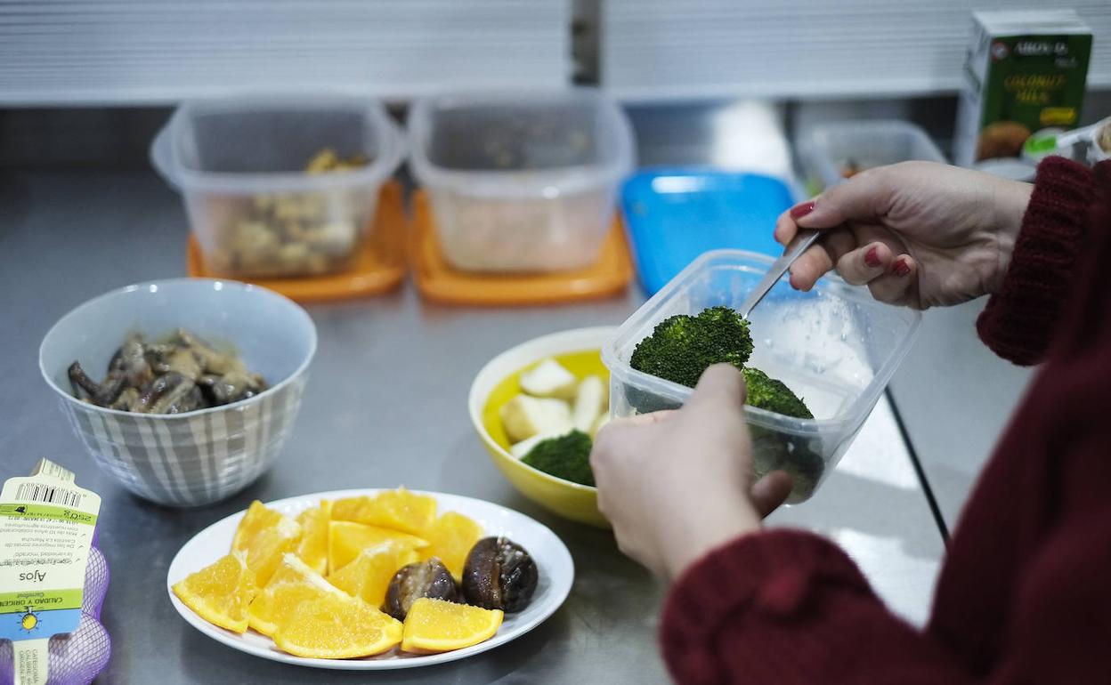 Una mujer prepara una comida con alimentos saludables.