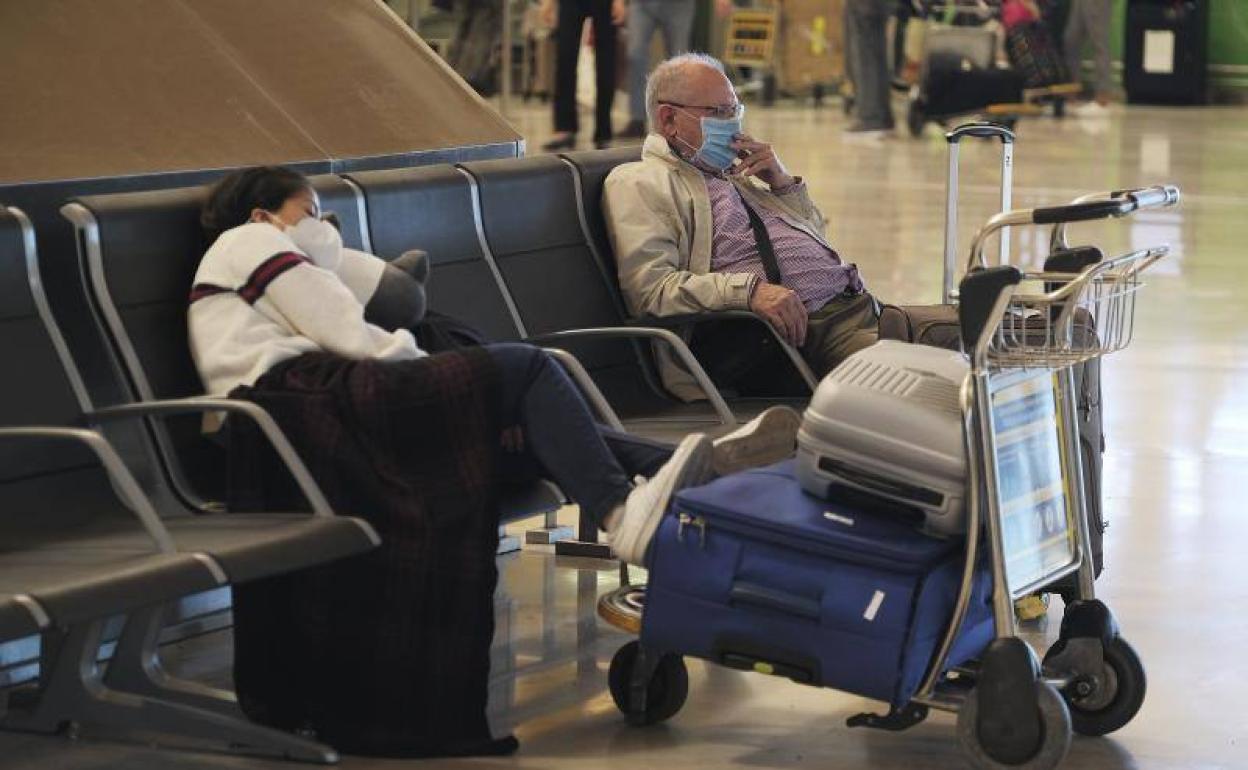 Viajeros esperan para acceder a su vuelo en el areopuerto de Barajas (Madrid).