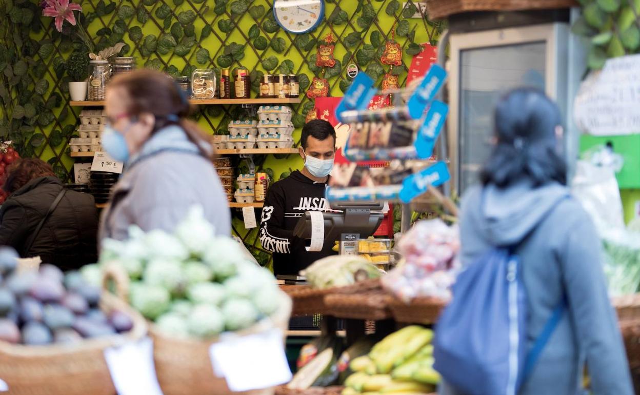 Una frutería con empleados y clientes con mascarilla.